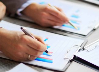 PEA : la solution pour défiscaliser les plus-values boursières ? Mains qui tiennent un stylo et qui écrivent sur un graphique