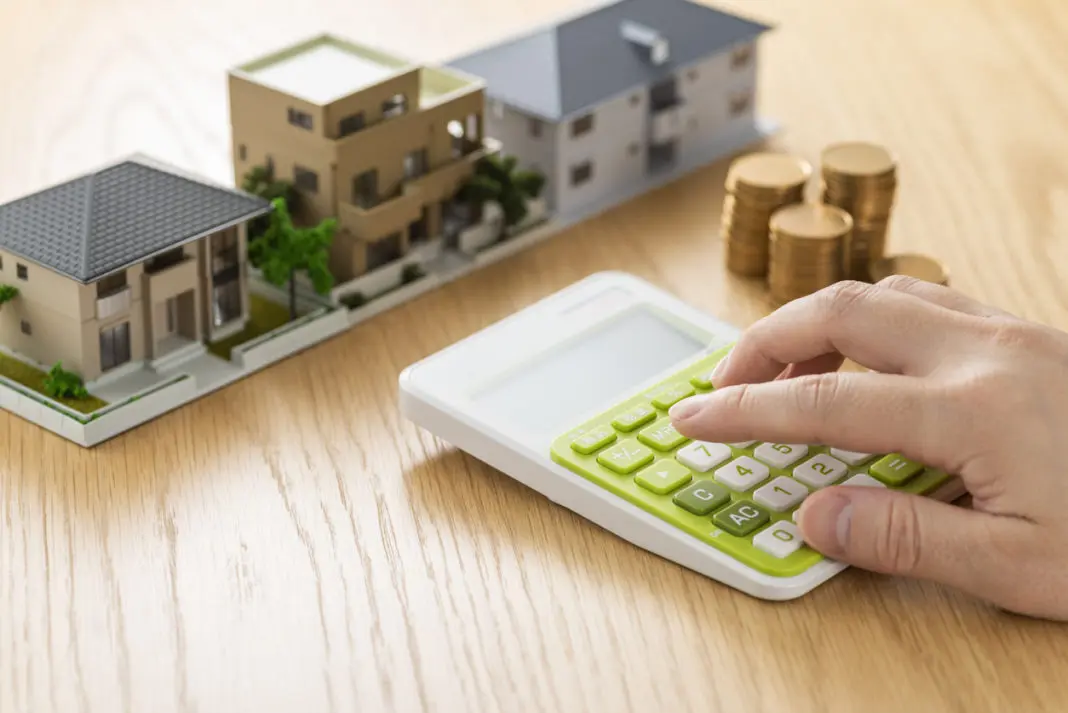 Une maquette d'une maison avec une calculatrice et des pièces de monnaie