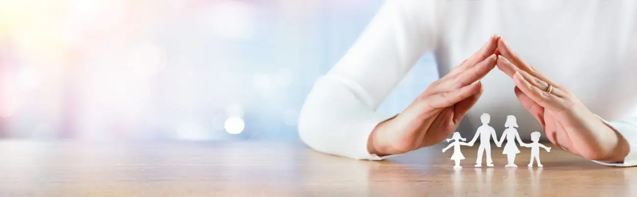 Des mains formant un toit avec des bonhommes en papier en dessous