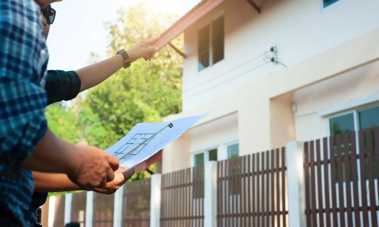 homme devant une maison avec les plans à la main