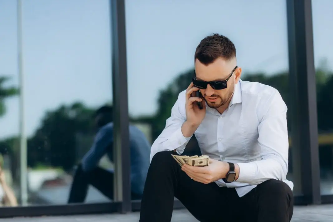 homme au telephone tient de l'argent